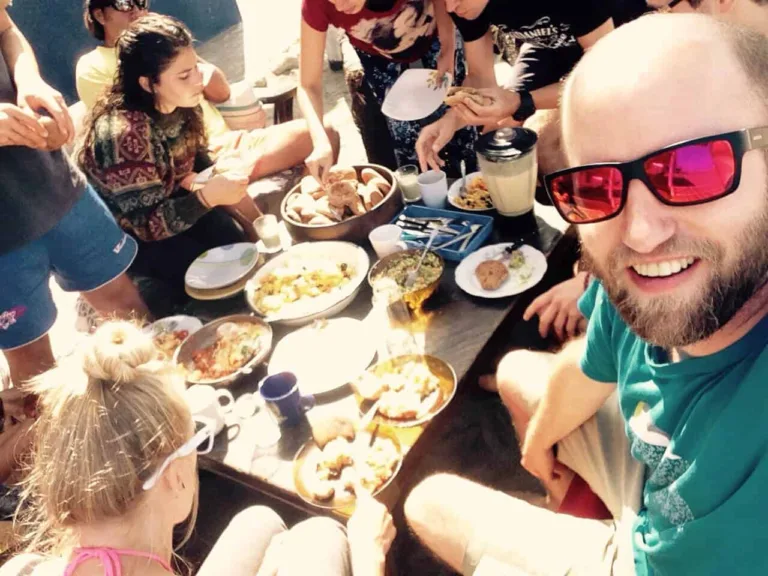 Selfie am Tisch mit einer Gruppe beim Essen, ein Mann mit roter Sonnenbrille lacht in die Kamera