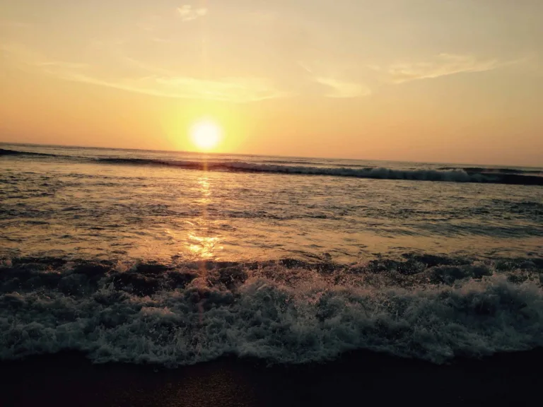 Sonnenuntergang über dem Meer mit auslaufenden Wellen im Vordergrund