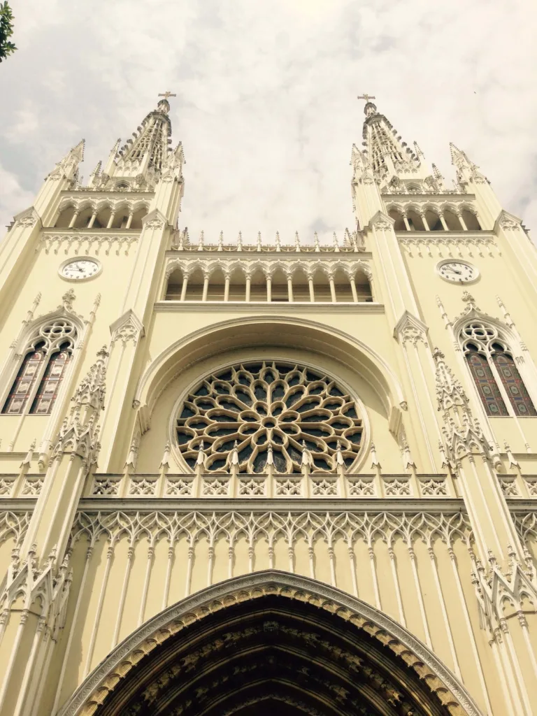 Helle Kirchenfassade im neugotischen Stil mit Rosettenfenster und zwei Türmen