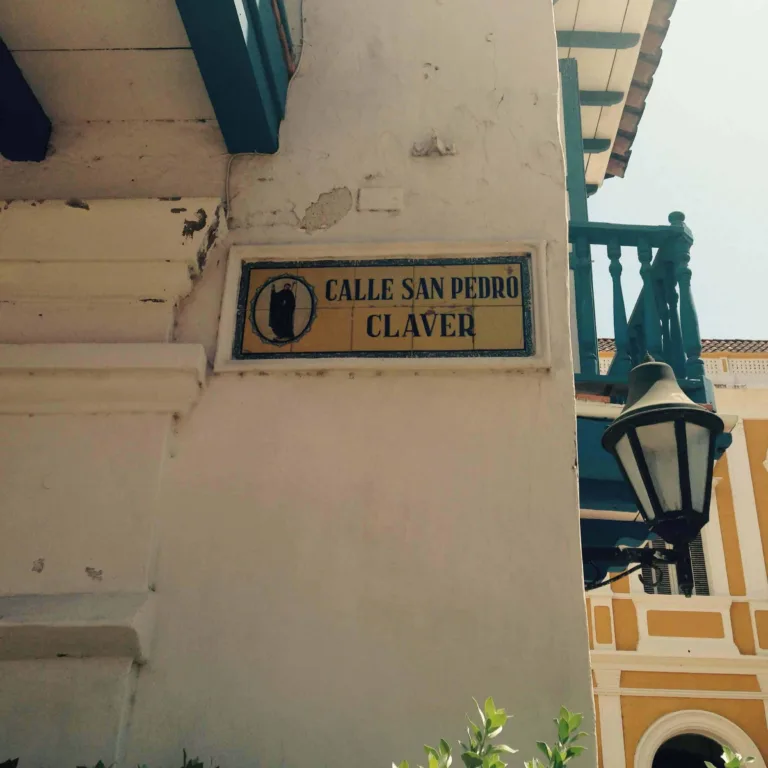 Strassenschild Calle San Pedro Claver an einer Hauswand, daneben eine Laterne und ein Balkon